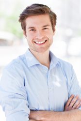 a handsome man with his arms crossed and big smile